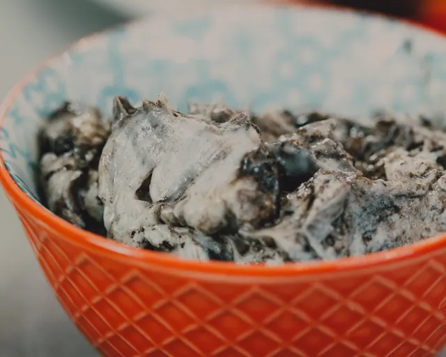 Grey, dark-speckled black sesame ice cream in an orange patterned bowl.