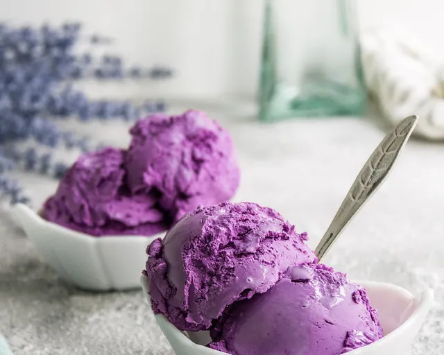 Deep purple grape sorbet in two small white bowls with a spoon.