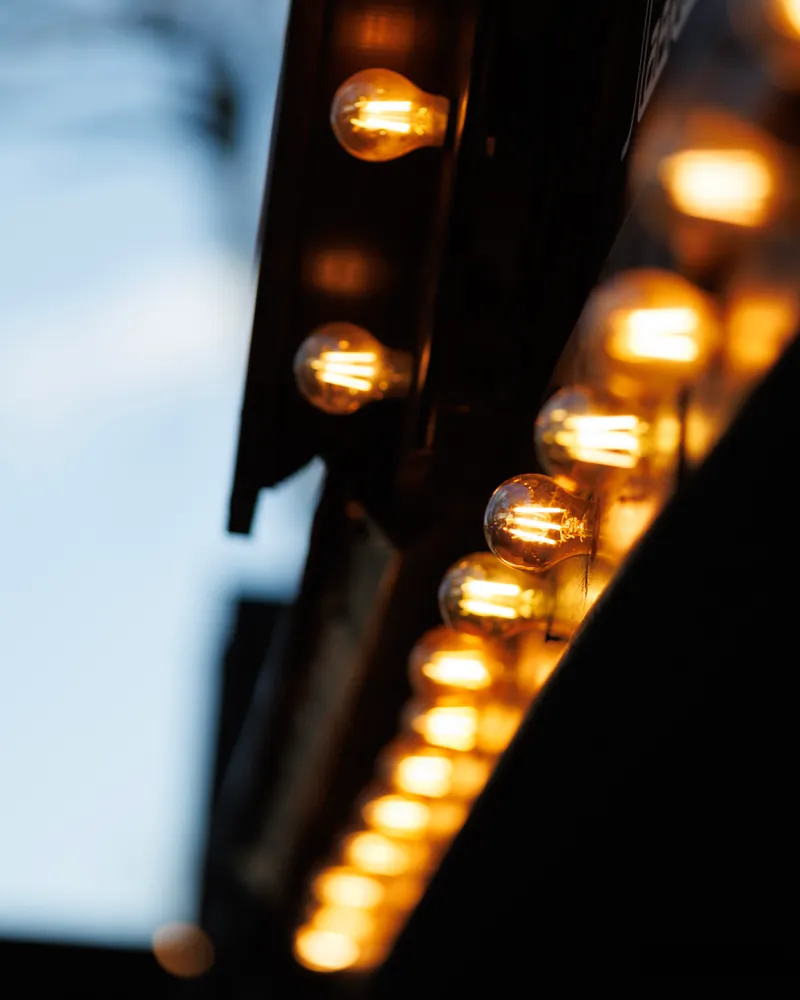 Warm bulbs along the edge of a cinema marquee at dusk.